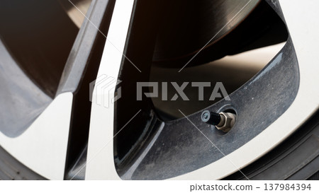 Detailed showing a black rubber tire valve stem with its protective cap. Essential component allows for air inflation and pressure monitoring to ensure vehicle safety and performance. Detailed showing a black rubber tire valve stem with its protective cap. Essential component allows for air inflation and pressure monitoring to ensure vehicle safety and performance. 137984394