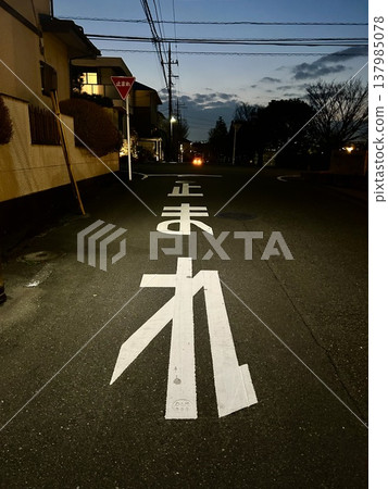黃昏時分的居民區,一個停車標誌和一條馬路-典型的日本景象。 黃昏時分的居民區,一個停車標誌和一條馬路-典型的日本景象。 137985078