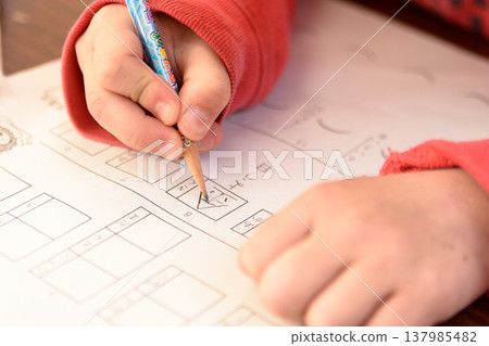 A child solving problems with a pencil: an image of a child's hands during basic learning. 137985482
