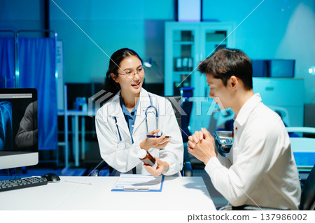 Asian female doctor consulting patient, taking medical history and explaining treatment in modern clinic Asian female doctor consulting patient, taking medical history and explaining treatment in modern clinic 137986002