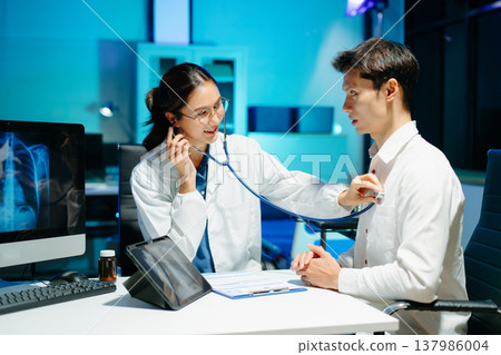 Professional doctor examining patient with stethoscope in modern clinic, healthcare consultation, medical checkup, diagnosis, trust, technology and wellness care. 137986004