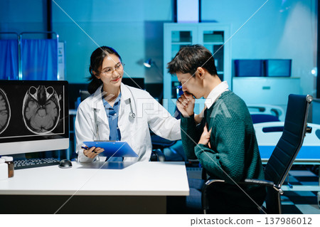 Female doctor reviewing brain MRI and notes during medical consultation with stressed male patient. Neurology diagnosis, mental health care and modern healthcare technology. Female doctor reviewing brain MRI and notes during medical consultation with stressed male patient. Neurology diagnosis, mental health care and modern healthcare technology. 137986012