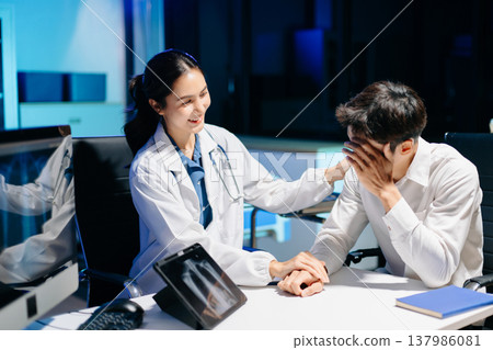 Asian doctor comforting stressed patient in hospital office, showing compassion, empathy, and emotional support during mental health consultation. Asian doctor comforting stressed patient in hospital office, showing compassion, empathy, and emotional support during mental health consultation. 137986081