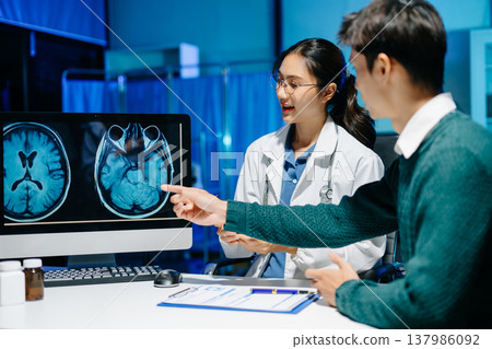Doctor explains brain MRI scan to patient during medical consultation. Neurology, diagnosis, healthcare, medical imaging, treatment and modern hospital concept. 137986092