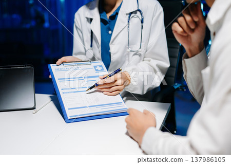 Asian doctor consulting patient in modern hospital office, explaining medical results and giving professional healthcare advice with friendly communication. Asian doctor consulting patient in modern hospital office, explaining medical results and giving professional healthcare advice with friendly communication. 137986105