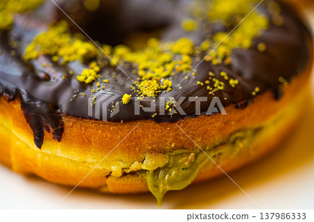 Dubai-style donuts with chocolate glaze, topped with chopped pistachios 137986333
