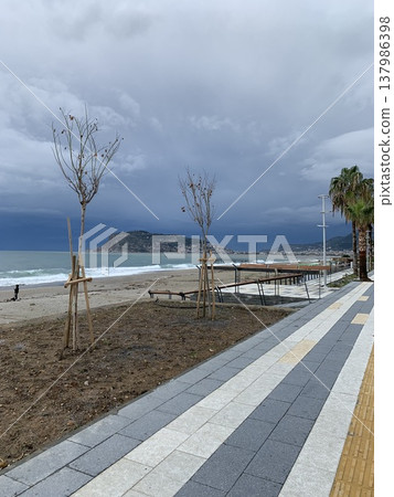 Beachside promenade with palm trees and stormy sky over ocean Beachside promenade with palm trees and stormy sky over ocean 137986398