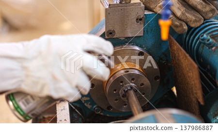 Worker lubricating machine part for industrial maintenance 137986887