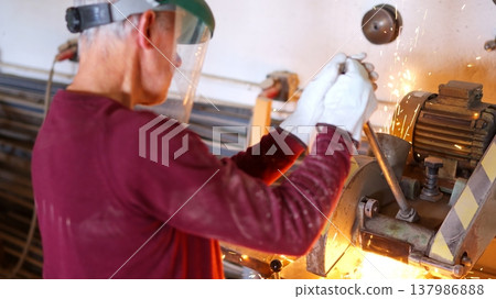 Worker shaping metal using grinder with sparks flying 137986888