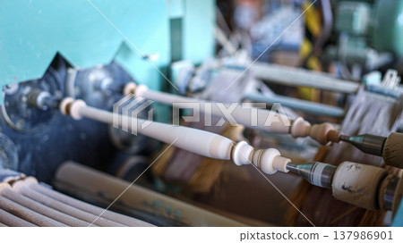 Wooden spindles being shaped on a woodworking lathe machine Wooden spindles being shaped on a woodworking lathe machine 137986901