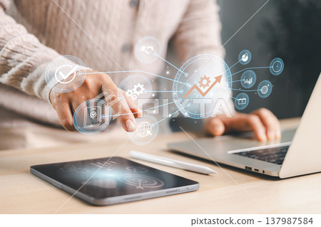 Professional using tablet and laptop with connected growth icons, showing productivity improvement, business strategy, performance tracking, workflow planning, optimization and digital success. 137987584