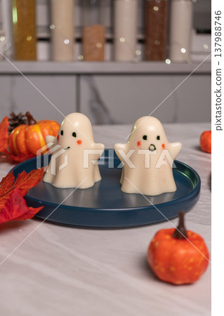 Cute ghost-shaped desserts on blue plate with mini pumpkins and autumn decor Cute ghost-shaped desserts on blue plate with mini pumpkins and autumn decor 137988746