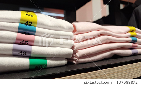 Neatly Stacked Clothing Display Featuring Various Sizes and Colors in a Retail Environment 137988872