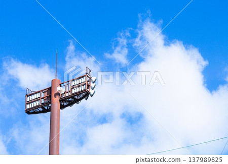 A simple scene with a refreshing blue sky, white clouds, and stadium lights. A simple scene with a refreshing blue sky, white clouds, and stadium lights. 137989825