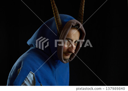 A portrait of a charismatic man in a medieval hood with pheasant feathers against a black background 137989840