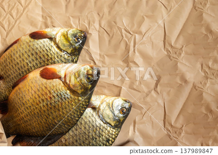 three fresh crucians on wrapping paper from the store. three fresh crucians on wrapping paper from the store. 137989847