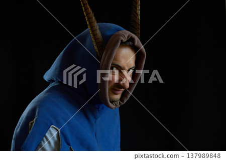Portrait of an angry man in a medieval hood with pheasant feathers on a black background Portrait of an angry man in a medieval hood with pheasant feathers on a black background 137989848