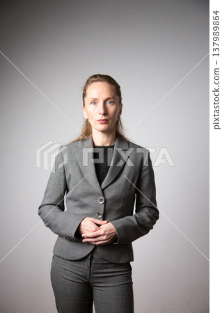 Vertical photo. A woman in a business suit with her arms folded. Vertical photo. A woman in a business suit with her arms folded. 137989864
