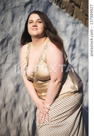 Portrait of a happy young woman against a wall. Body positivity. Vertical photo Portrait of a happy young woman against a wall. Body positivity. Vertical photo 137989927