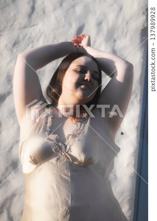 Portrait of a happy young woman in the sun against a wall. Body positivity. Vertical photo. Portrait of a happy young woman in the sun against a wall. Body positivity. Vertical photo. 137989928