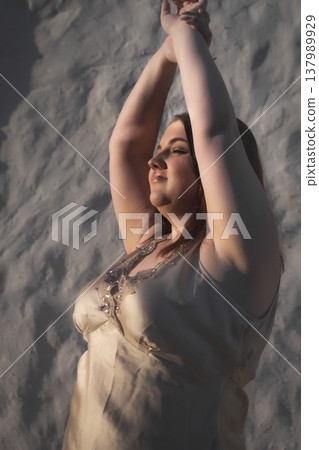 Portrait of a happy young woman in the rays of the sunset against a wall. Body positivity. Portrait of a happy young woman in the rays of the sunset against a wall. Body positivity. 137989929