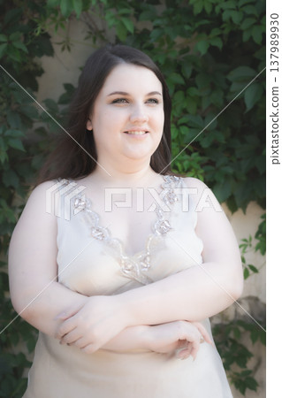 Portrait of a happy young woman against a green backdrop. Body positivity. Vertical photo. Portrait of a happy young woman against a green backdrop. Body positivity. Vertical photo. 137989930