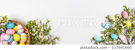 Easter colored painted eggs in basket and blooming spring cherry branches on gray background in shape of frame with space for text and greetings. Easter and spring concept. Spring background Easter colored painted eggs in basket and blooming spring cherry branches on gray background in shape of frame with space for text and greetings. Easter and spring concept. Spring background 137991660