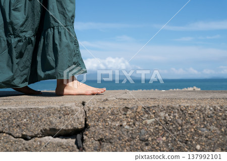 一位女子赤腳走在海堤上。 137992101