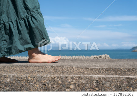 一位女子赤腳走在海堤上。 137992102