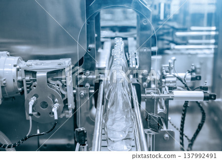 The hi-technology of drinking water manufacturing process. The empty drinking water bottles on the conveyor belt for filling process. The hi-technology of drinking water manufacturing process. The empty drinking water bottles on the conveyor belt for filling process. 137992491