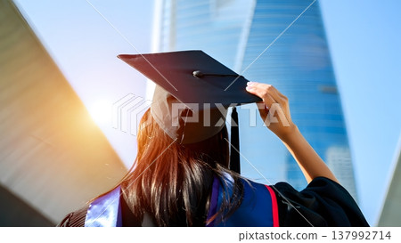 Celebrating Graduation with Cap Against Modern Architecture Background 137992714