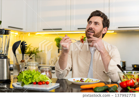 Middle-aged man enjoying fresh vegetable salad meal in home kitchen for healthy diet daily nutrition Middle-aged man enjoying fresh vegetable salad meal in home kitchen for healthy diet daily nutrition 137992778