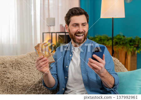 Man checking balance on smartphone, excited about received money, celebrating lottery or game win Man checking balance on smartphone, excited about received money, celebrating lottery or game win 137992961