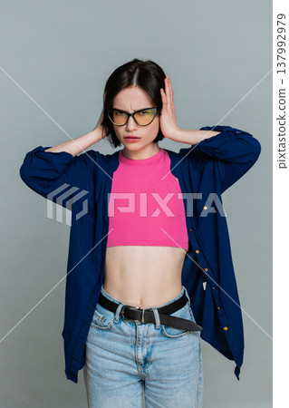 Woman covering ears with hands turning head away indicating unwillingness to hear refuse gesture Woman covering ears with hands turning head away indicating unwillingness to hear refuse gesture 137992979