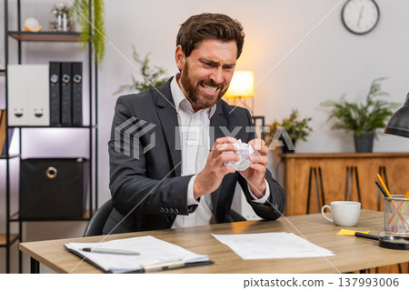 Middle-aged businessman manager crushes faulty report exhales hard calms and returns to edit again 137993006