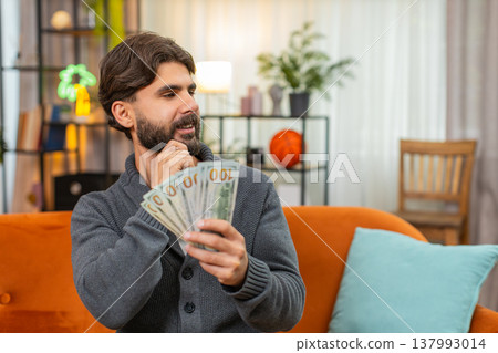 Indian man counts dollar cash banknotes dreams of travel thinks where to spend money smiles wealthy Indian man counts dollar cash banknotes dreams of travel thinks where to spend money smiles wealthy 137993014