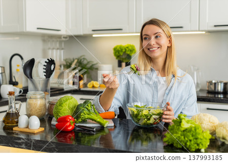 Young woman eating fresh vegetable salad for keto vegetarian meal in modern home kitchen lifestyle Young woman eating fresh vegetable salad for keto vegetarian meal in modern home kitchen lifestyle 137993185