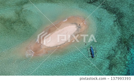Aerial pristine white sandbar surrounded by crystal turquoise water with a traditional outrigger boat moored nearby, tranquil, secluded tropical travel and paradise serenity. East Gili Islands, Lombok Aerial pristine white sandbar surrounded by crystal turquoise water with a traditional outrigger boat moored nearby, tranquil, secluded tropical travel and paradise serenity. East Gili Islands, Lombok 137993393