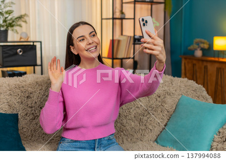 Young woman on sofa having video call laughing and using expressive hand gestures with real emotion Young woman on sofa having video call laughing and using expressive hand gestures with real emotion 137994088