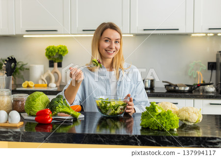 Young woman eating fresh vegetable salad for keto vegan diet and healthy nutrition at home kitchen Young woman eating fresh vegetable salad for keto vegan diet and healthy nutrition at home kitchen 137994117