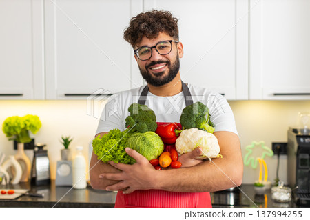 Man holding fresh vegetables close up in red apron for healthy meal prep nutrition in home kitchen 137994255