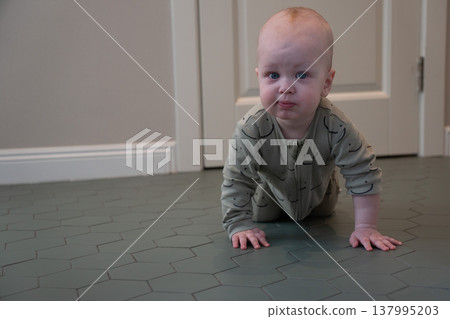 Baby crawls on floor in home interior with soft light and minimal setting, early development stage and exploration in everyday domestic environment. Child development, parenting content, family 137995203