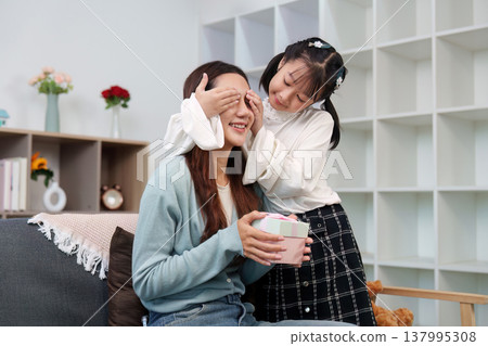 Child surprising mother with a gift at home Child surprising mother with a gift at home 137995308