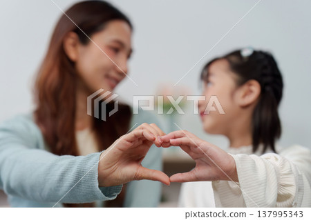 Mother and daughter forming a heart with hands 137995343
