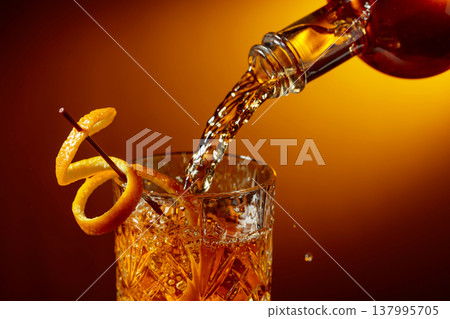 Whiskey or bourbon pouring into a crystal glass. Whiskey or bourbon pouring into a crystal glass. 137995705