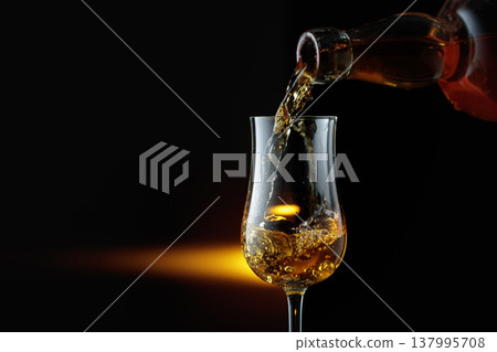 Rum being poured from a bottle into a glass. 137995708