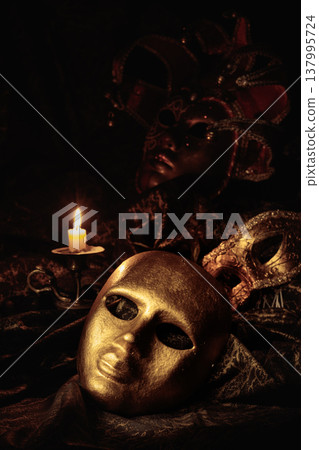 Golden carnival masks and burning candle in old brass candlestick. Golden carnival masks and burning candle in old brass candlestick. 137995724