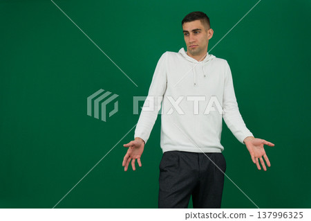 Young man shrugging with a confused expression, wearing white clothes. 137996325