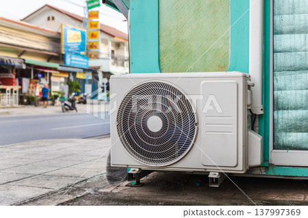 Outdoor air conditioner unit mounted on small street kiosk near road with scooters 137997369