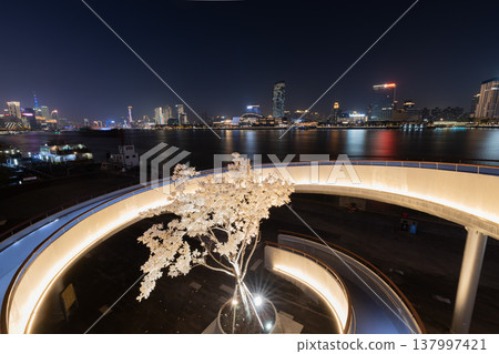 從上海浦東濱水區眺望黃浦江夜景，可以看到螺旋坡上的玉蘭花花在燈光的映襯下，以及浦西的城市天際線。 137997421
